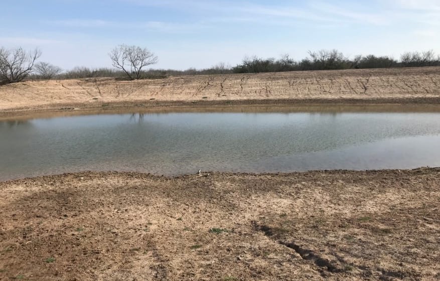 Water-filled pond with graded bank from prior work