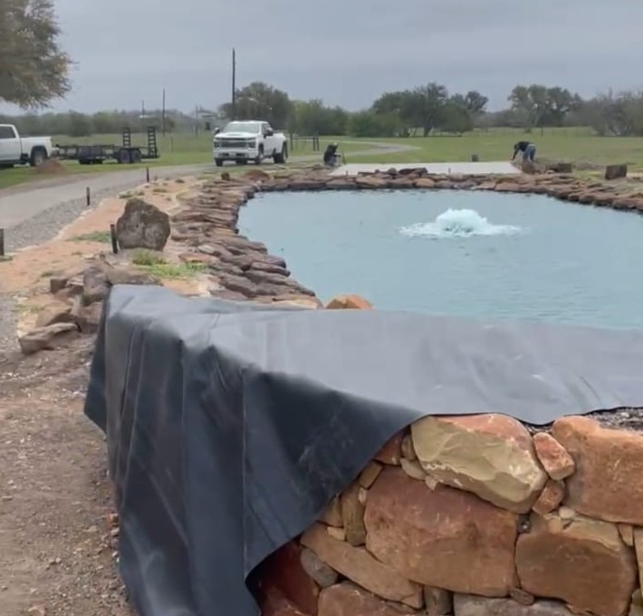 Stone-walled pond with liner and water from prior work